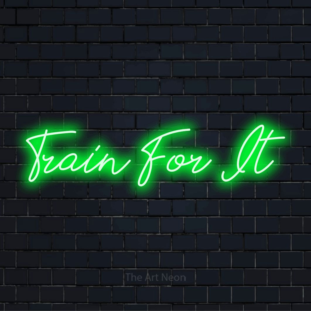 "Train For It" LED neon sign on a black brick wall