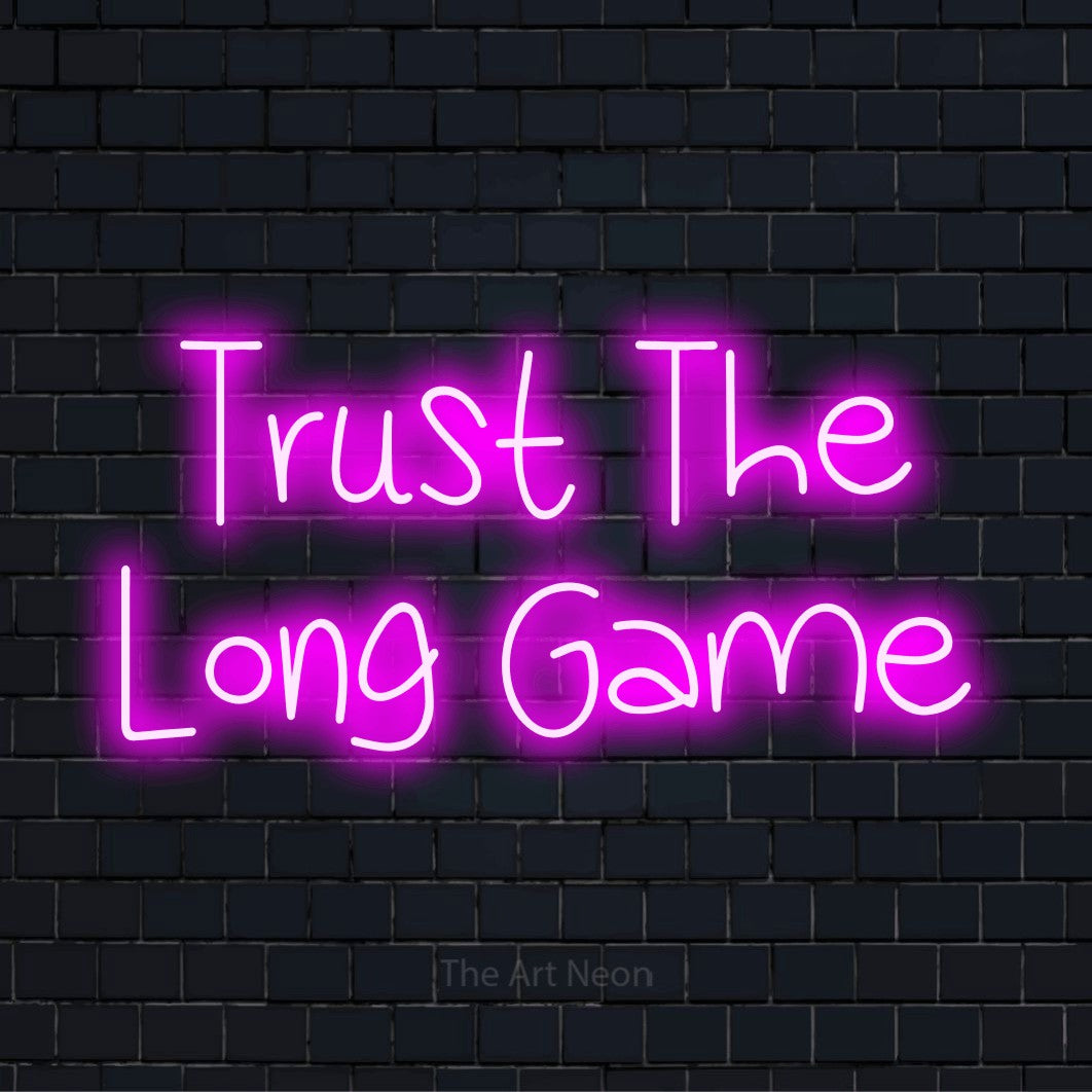 "Trust The Long Game" text design with neon effect on a black brick wall