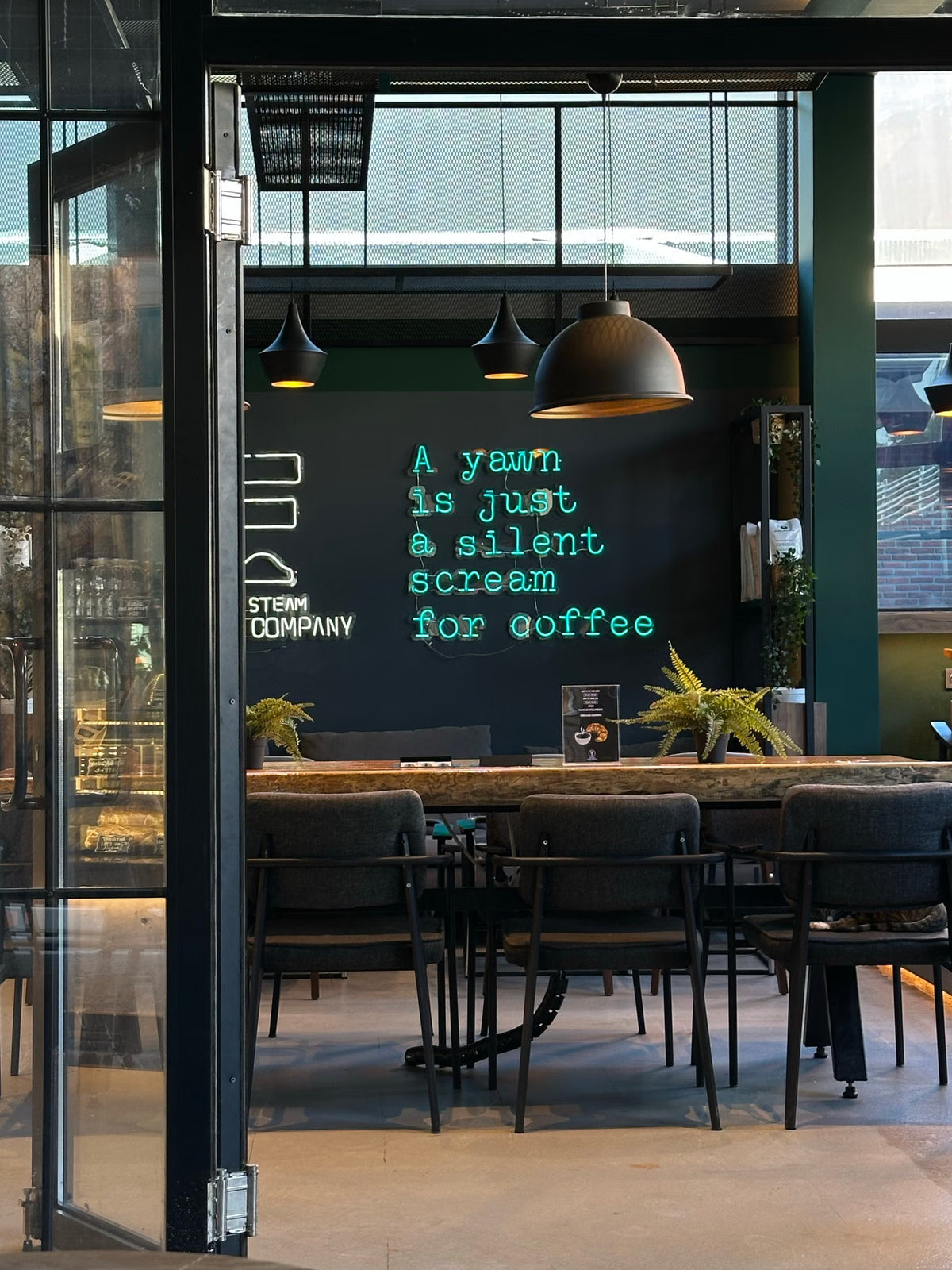 Türkisfarbenes LED-Neonschild mit Zitat in einem Café