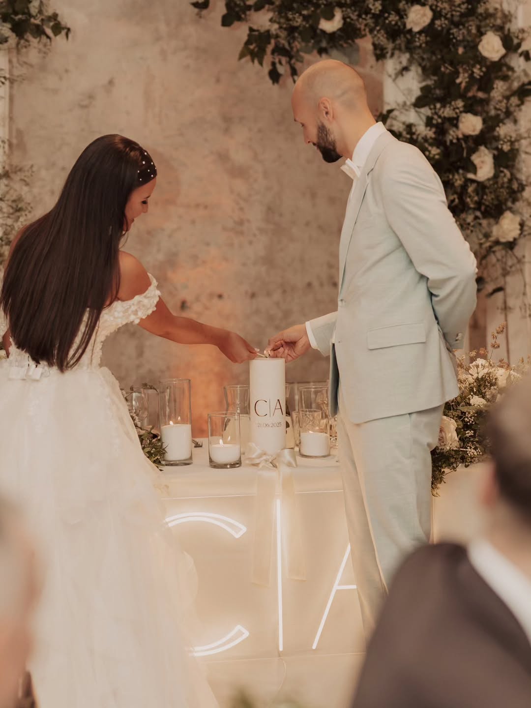 LED-Neonschild mit den Initialen C und A über einem Hochzeitstisch bei Kerzenlicht