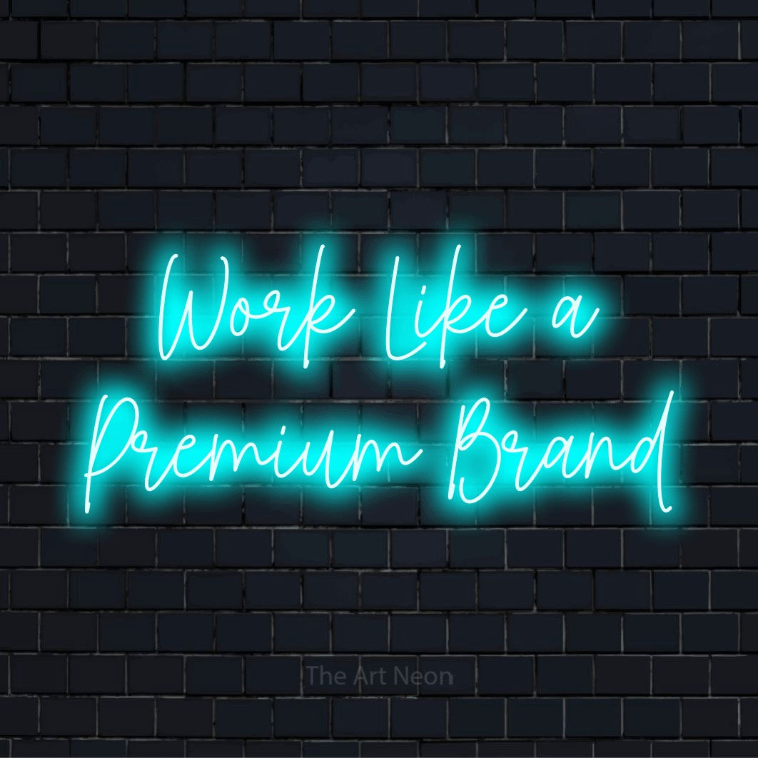 "Work Like A Premium Brand" script-style LED neon sign on a black brick wall