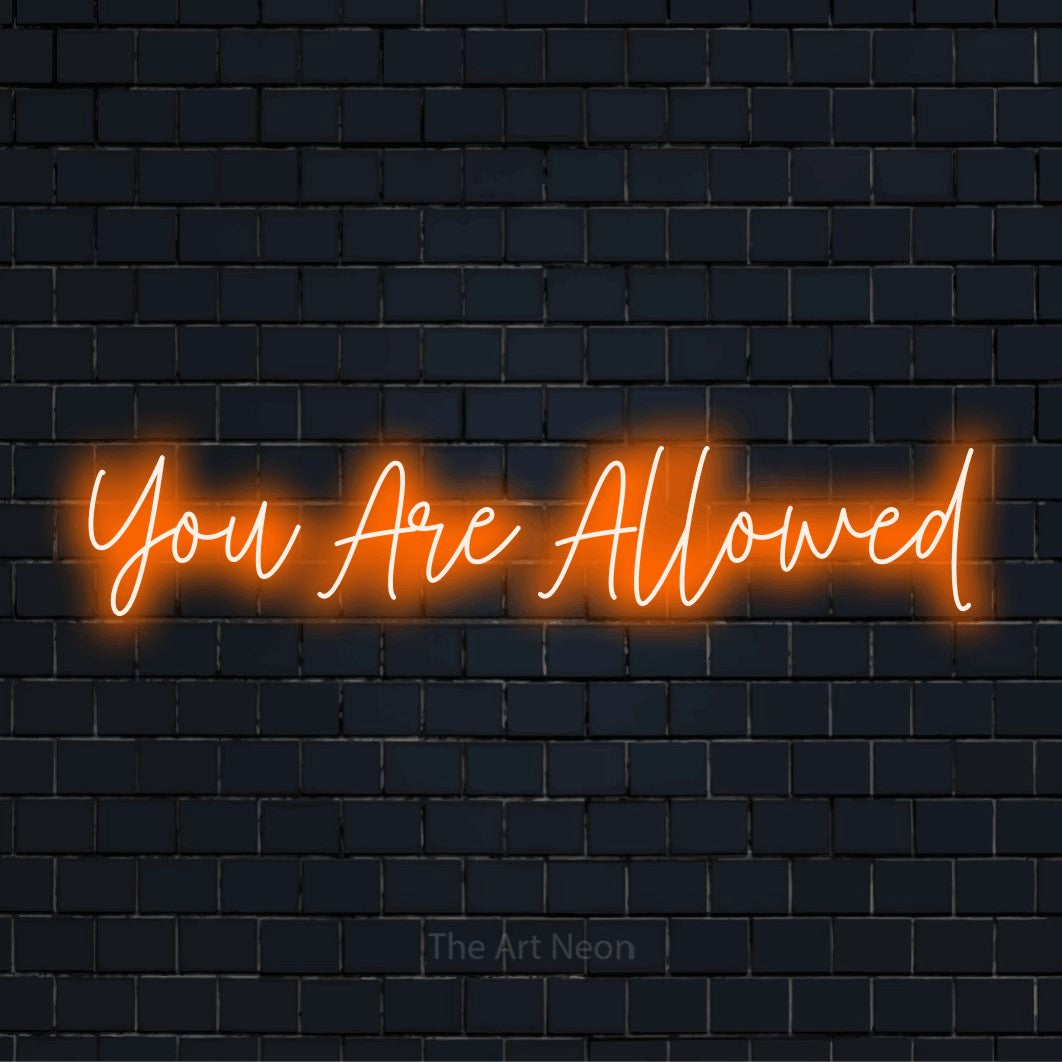 "You Are Allowed" script-style LED neon sign on a black brick wall