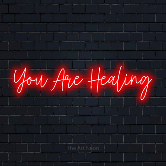 "You Are Healing" LED neon sign on a black brick wall