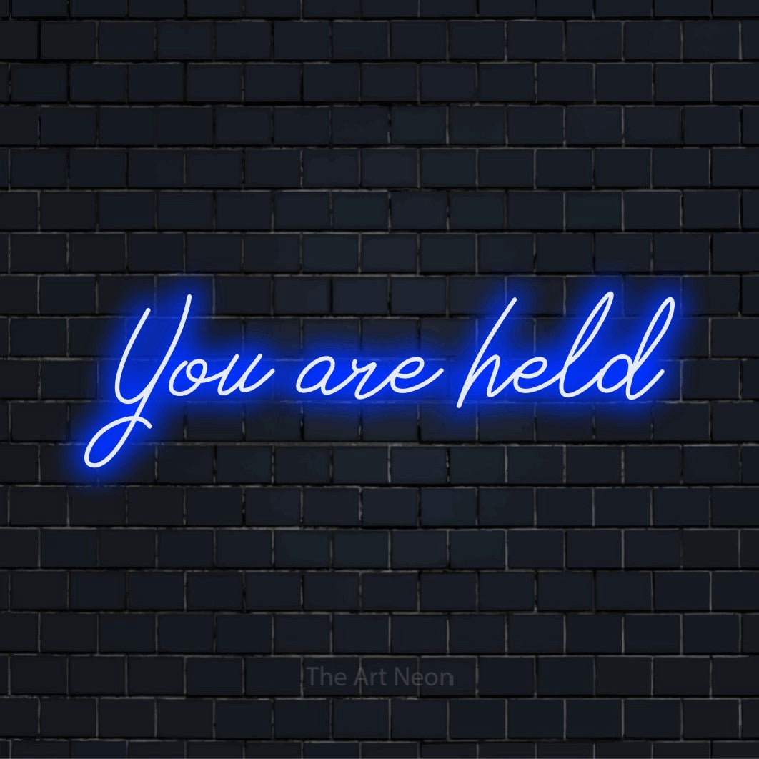 "You Are Held" glowing LED neon sign on a black brick wall