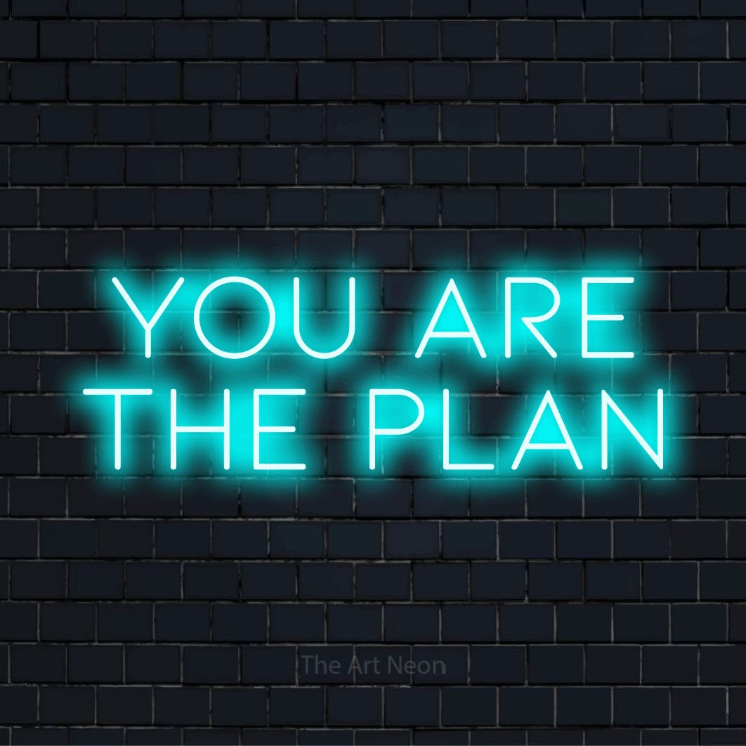 "You Are The Plan" LED neon sign on a black brick wall