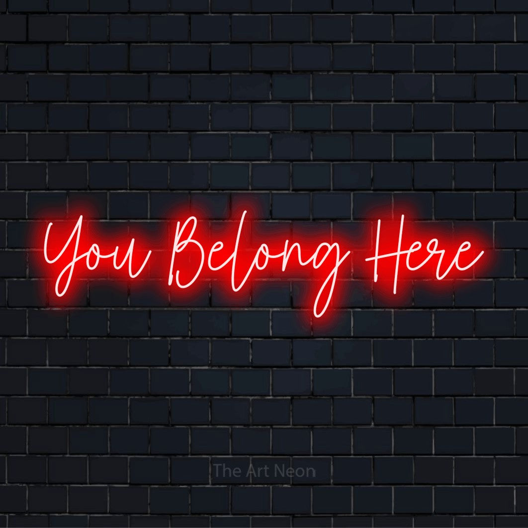 "You Belong Here" glowing LED neon sign on a black brick wall