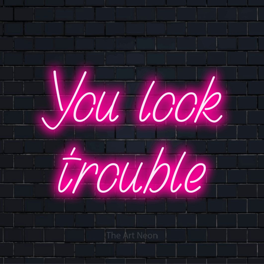 "You Look Trouble" glowing LED neon sign on a black brick wall