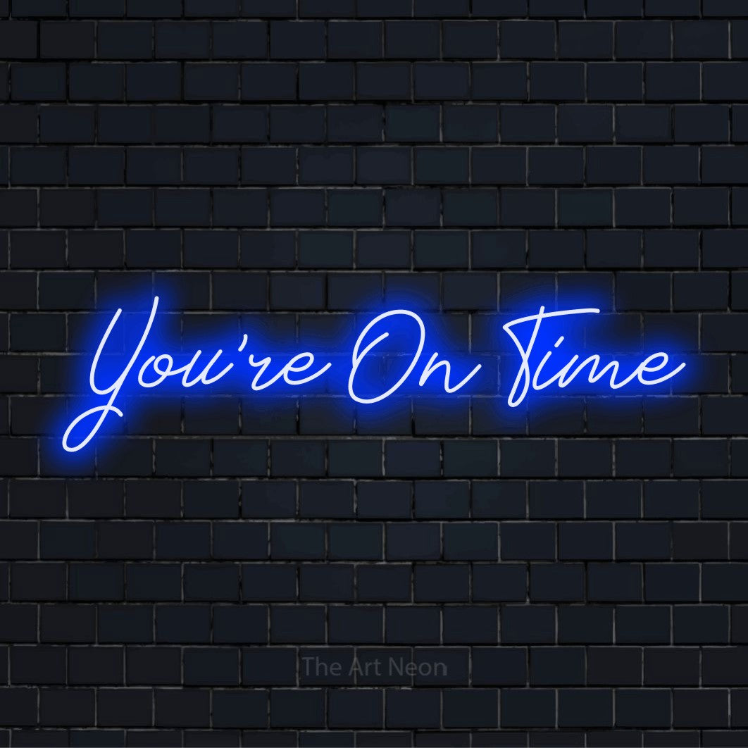 "You’re On Time" neon text design on a black brick wall